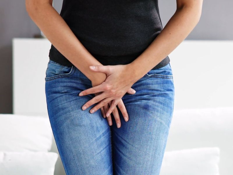 devojka u farmerkama i crnoj majici drži se dole od bola