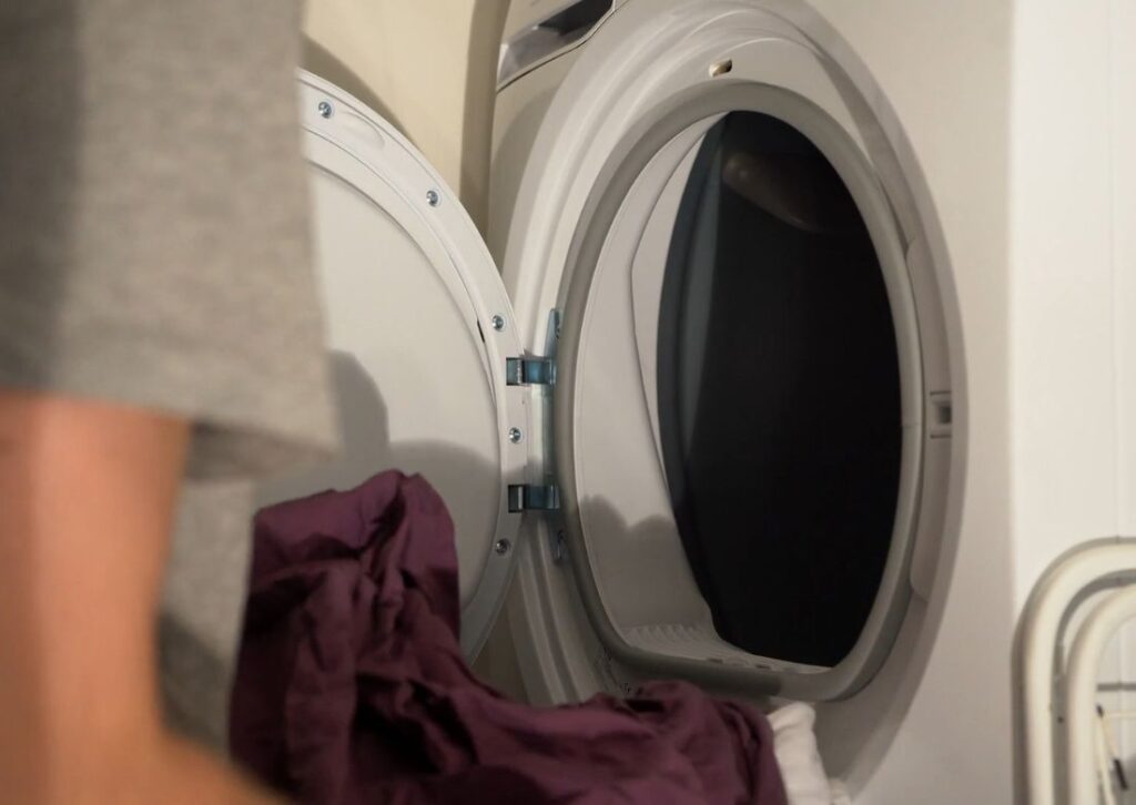 osoba vadi veš iz mašine za sušenje veša